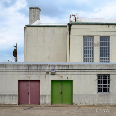 A large, gymnasium like building housing the Illinois National Guard with large, multi-pane windows and a pair of double doors - one set green and the other a faded purple.