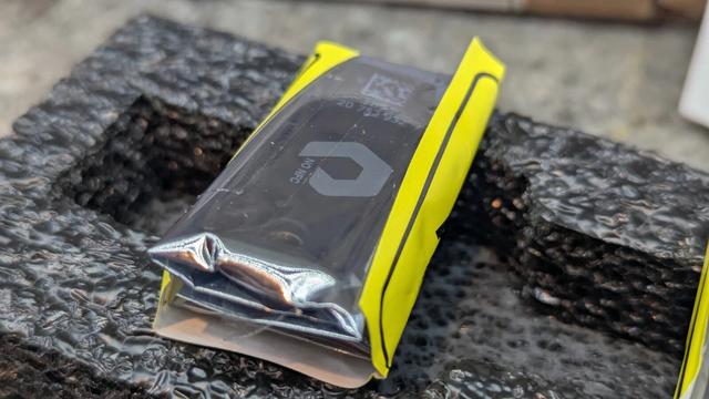 Closeup of YubiKey in a transparent antistatic bag. Key is oriented "portrait", angled away. Through the bag, the QR-like code, the serial, the "FIPS" label, and the PureStorage logo can be seen.