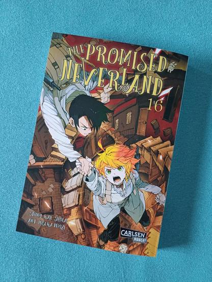 Das Foto zeigt das Cover des 16. Bandes des Manga 'The promised neverland' mit den beiden Hauptcharakteren Emma und Ray.