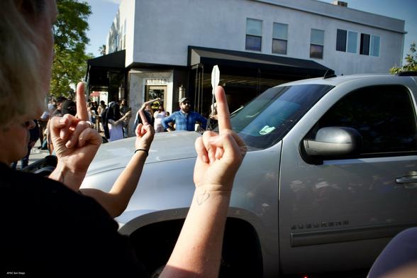 People on street flip off ICE van.