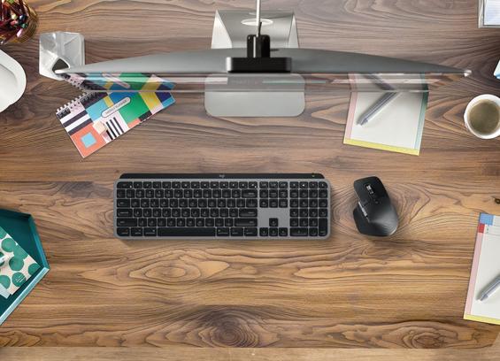 Schreibtisch aus der Vogelperspektive mit Logitech-Tastatur und -Maus vor einem Bildschirm. Foto (c) Logitech.