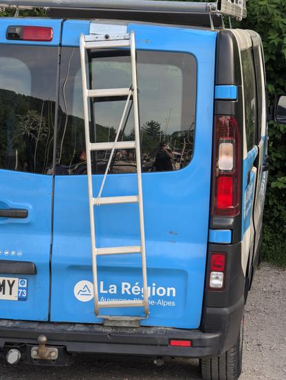Camion  logoté Auvergne Rhône Alpes avec une échelle installée de biais sur le hublot arrière.