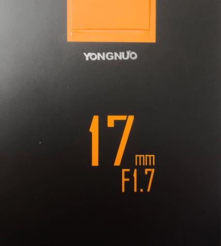 Umverpackung von dem Objektiv YONGNUO 17mm F1.7 Schrift ist teilweise  in Orange auf schwarzem Hintergrund.