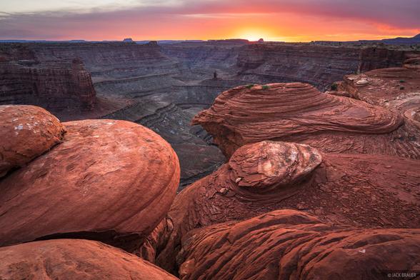 A glowing sunset over a remote canyon near the Colorado River and the Needles District of Canyonlands National Park, Utah.