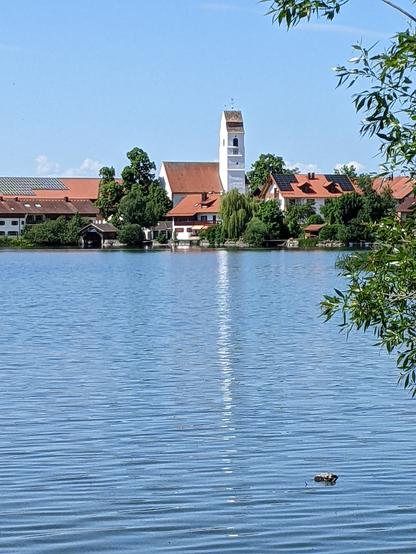 Bavaria village church its reflection seen across lake Riegsee