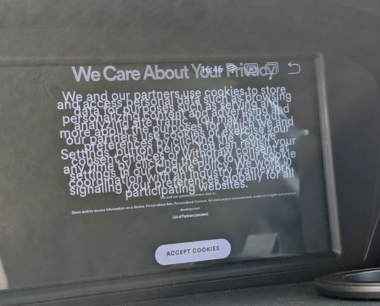 Photo of in-car Android screen showing Spotify cookie consent prompt titled "We Care About Your Privacy". the font size for most of the body text is too large and lines are overlapping.
