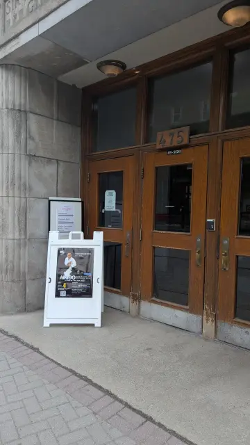 A sign in front of a set of doors announcing an aikido seminar.
