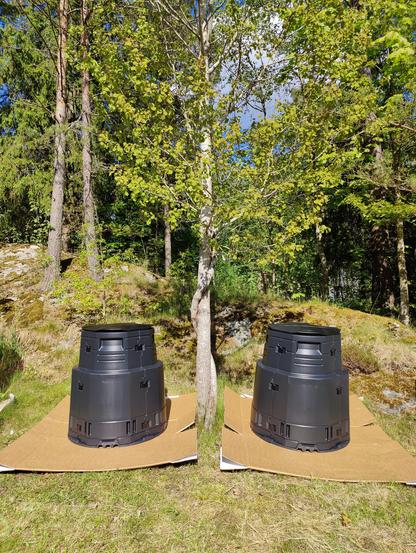 Two black compost bins placed on either side of a tree.
