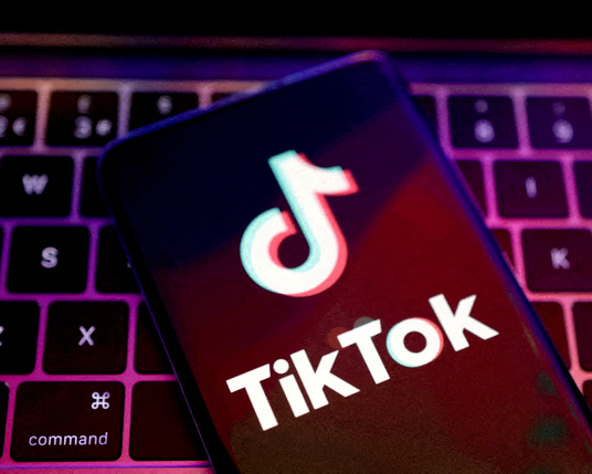 Photo image - a keyboard with a mobile device in front of it with a TikTok logo