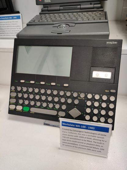 A charcoal-coloured plastic slab with a postcard-sized LCD screen. The circular grey keyboard and numpad keys resemble those on the Sinclair QL, or some of Olivetti's virtuoso designs.

The copy from the explanatory label:

Workslate WK-100 - 1983

Created by Convergent Technologies of Santa Clara, California, this was a portable spreadsheet device with 16KB of RAM, allowing for a 720-cell spreadsheet to be filled. The built in tape drive could record or playback data or voice annotations. A commercial failure, only 5,000 systems of the planned 200,000 were sold.