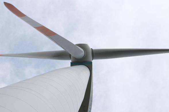 A large wind turbine. Photo taken from below right at the stem up towards the turbine housing and rotor.