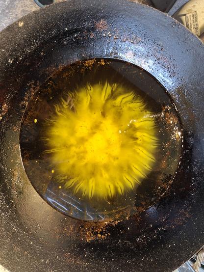 We look straight down into the center of a very large wok. It is filled with opaque yellow frying oil that turns clear when melted. Part of the oil has indeed meltet in a pattern that vaguely hints at the outer fringes of a sunflower. 

There are cloudy parts in the middle. Towards the edge of the not-yet-liquid part clear streaks have formed, contrasted by solid yellow oil around the streaks.