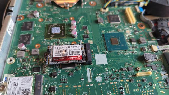 Closeup of the motherboard inside a Lenovo All In One desktop PC. The motherboard resembles a laptop board more than a desktop, but all the key components are there. Some of the old thermal paste is visible on a chip near the top of the frame. An NVMe drive is visible; unfortunately it wasn't recognized by the system so I removed it.