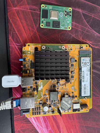 Home Assistant Yellow with its case off, showing a new Raspberry Pi CM5 fitted along with a Samsung NVMe drive and Aeotec ZWave and Zigbee sticks in the USB ports. The old CM4 module sits beside the device.