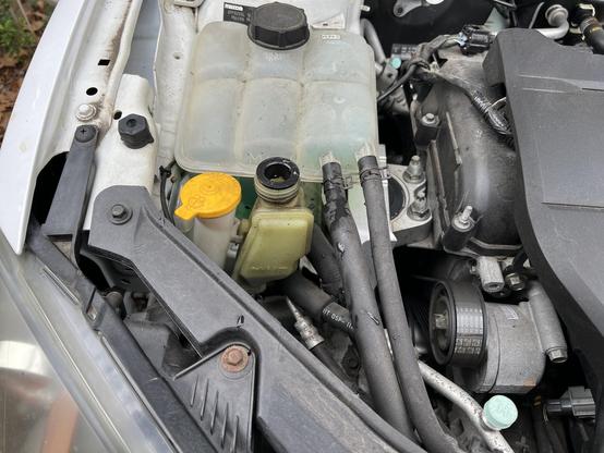 Front left view of an open Mazda 3 engine bay. Reservoir next to wiper reservoir has no cap???