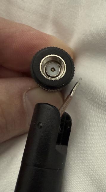 A close up picture of a WiFi antenna showing the connector separated from its body. What should be an outie in the middle of the connector circle is not protruding as it should