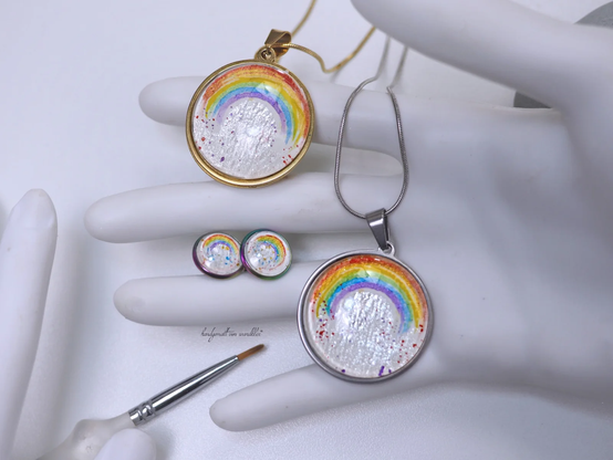 Halsschmuck und Ohrringe mit stilisiertem Regenbogensymbol