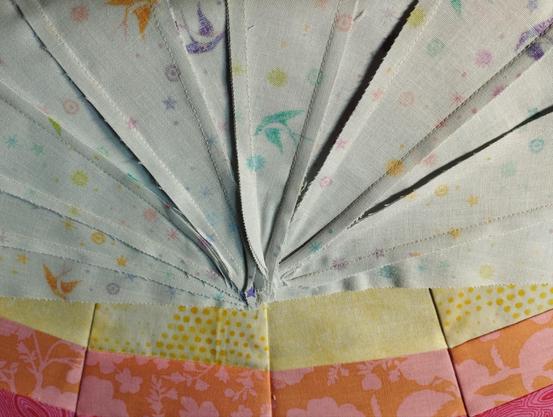 Photo of the backside of a sewn piece of fabric. Many seams come together at one middle point and the seam allowance overlaps chaotically.