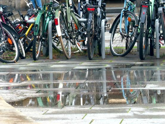 Fahrräder, die sich in einer Pfütze spiegeln.