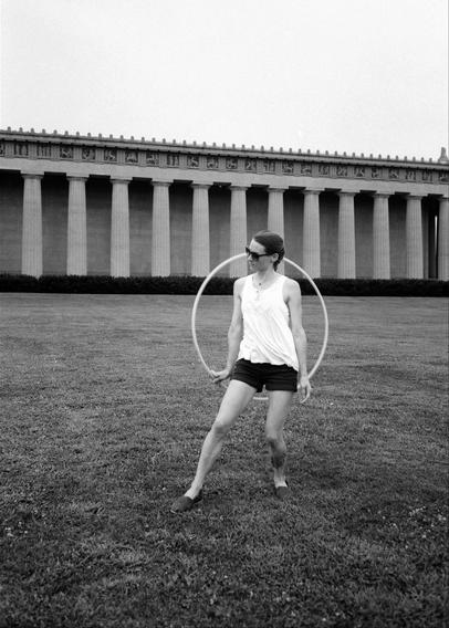 Black and white photo of a young woman practicing her hooping on the lawn of the Nashville Parthenon — a full-scale replica of the original in Greece.

Photo taken with an Olympus Epic Stylus DLX camera on black and white film (July 2017).
