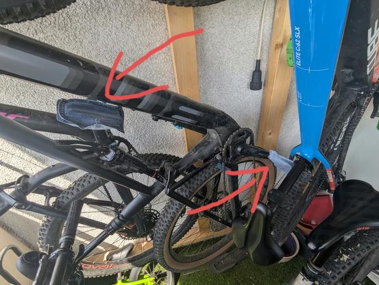 Zwei bikes hängen an einer Wand. Zwei rote Pfeile zeigen auf die jeans Überzüge auf den Pedalen