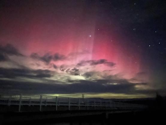 Cloudy sky with pink and green aurora. There are curtains and beams.