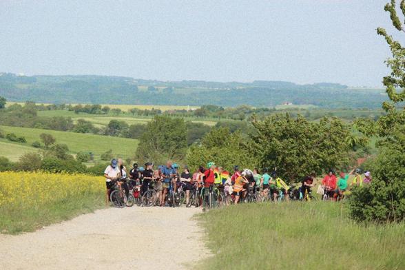 Foto von fahradfahrenden Menschen auf einem staubigen Kiesweg pausierend.