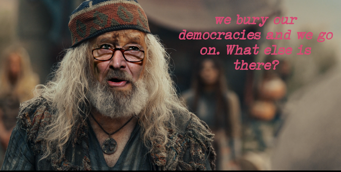 schumer,  chuck  Democratic leaders face blended into  the  face of the  Aiel leader from  Wheel  of Time.  He wears a hand knit cap  in red  green  and blue  his hair is long and white as is his full beard -his trademar glasses ar on his nose : captioned :  We bury our Democracies and we go on  .  What else is there?