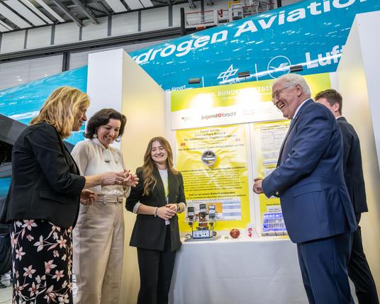 Am Präsentationsstand des Projekts "Power inside: eine essbare Batterie für nichtinvasive Diagnoseverfahren": Bundesbildungsministerin Karin Prien, Bundesforschungsministerin Dorothee Bär, die Jungforscherin Elisabeth Fischermann, Bundespräsident Frank-Walter Steinmeier und Jungforscher Tom Kreßbach (v.l.n.r.). Das Projekt siegte in der Sparte Chemie.