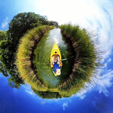 One of a series of photographs in which two people are pictured hiking, biking, and kayaking throughout a beautiful and verdant state park in central Minnesota under cloudy blue late-summer skies.
