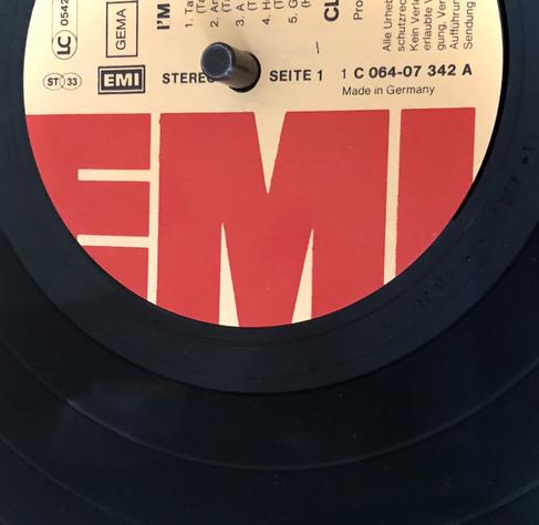 Ein Ausschnitt einen Schallplatte. Auf der Mitte ist in roten Buchstaben EMI zu lesen, in klein „Stereo“, Bestellnummer, „Gema“ „Made in Germany“ und auch „Seite 1“. (Titel und Interpreten sind nicht im Bild.)