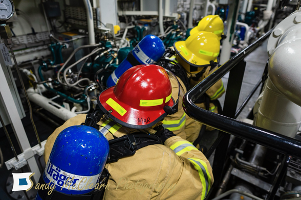 Damage control team in firefighter gear practicing in a ship’s engine room.