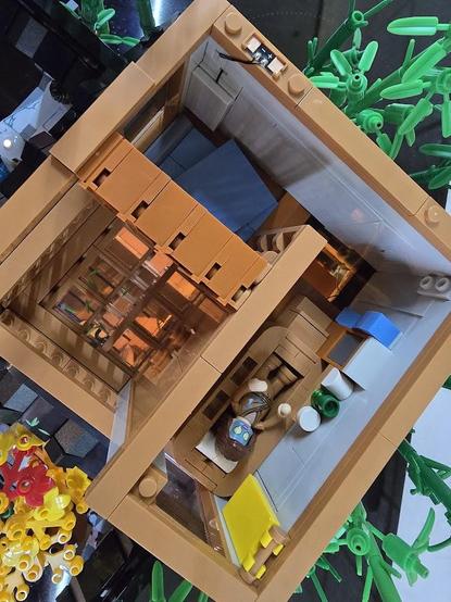Eine Sicht von oben in der obere Stockwerk des Klemmbaustein-Haus bei abgenommenem Dach. Zu sehen ist eine Loggia mit Glasboden, ein Schlafraum und ein Badezimmer. In der Wanne liegt eine Person die anscheinend eine Gurkenmaske trägt.