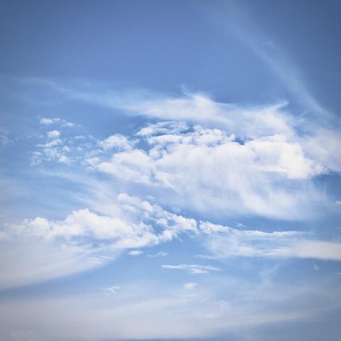 What look to be stratus clouds wisp throughout the frame against a bright blue afternoon sky.