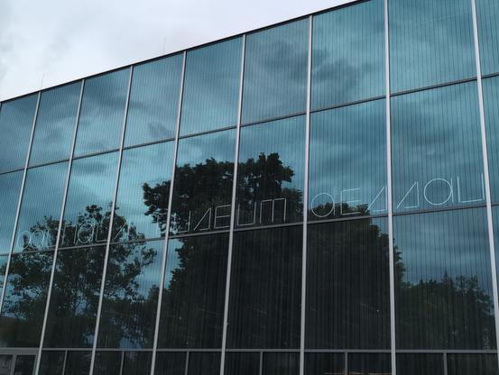 Aussenfassade des Bauhaus Museum in Dessau.
Eine Glasfront mit dem Schriftzug "bauhaus museum dessau" dahinter.