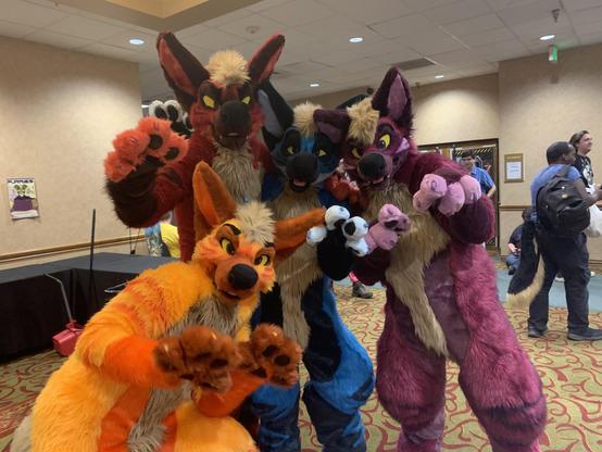 4 nearly-identical hyena fursuits of different colors. From left to right: Tangelo (orange), Caliente (red), Rally (blue), and Spark (purple)