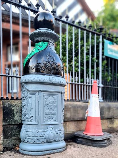 A decorative iron lamp base which is in the process of being decorated.
