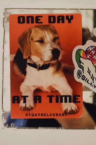 A sticker stating "one day at a time" with a dog.