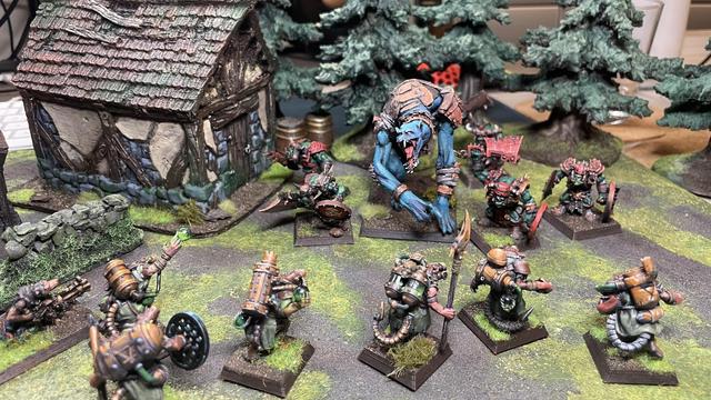3/4 view shot of the previous scene, you can more clearly see the giants features, as well as the board and scenery.

Previous description:

A giant blue humanoid screeches as it breeches a tree line towards a team of skaven globadiers. It’s blue skin barely covered with leather wrapping and rusty armour. A skirmish team of orcs accompany its charge.