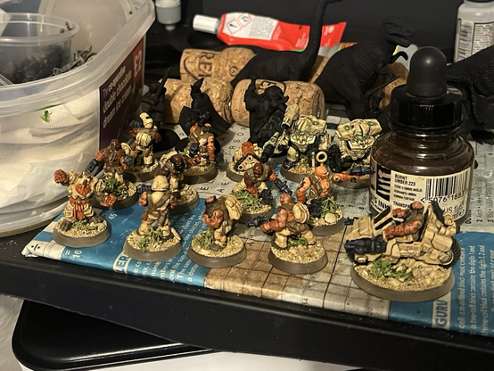 A collection of Forge Father minis on a painting desk. They are nearly finished.