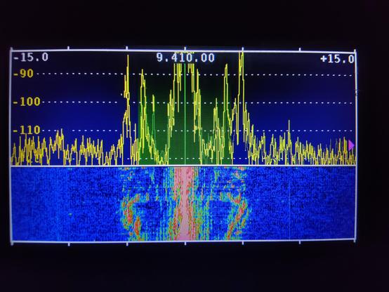 A picture of spectrum display and waterfall display of a shortwave radio station. It is a highly colourful display. The different colours represent the strength (and the frequencies) of the radio waves being transmitted.