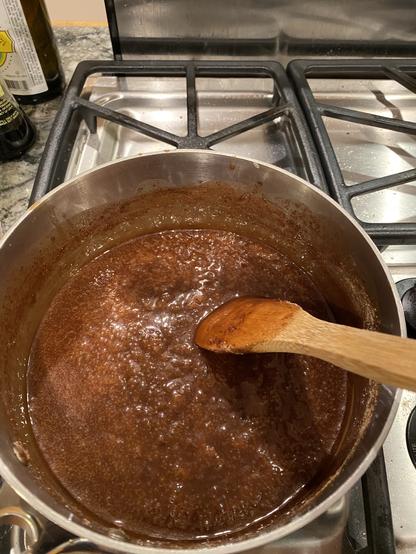 bubbling fudge in a pot with a wooden spoon