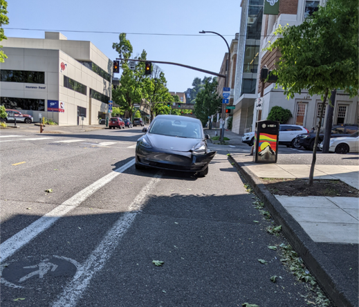 Tesla with a broken bumper parked facing the wrong way on Broadway protected bike lane, right next to two empty designated car storage spots, also missing the required front plate, does the dealership not provide the bracket?  Maybe we should require that to match the state law.  This bike lane should be protected by more than paint.