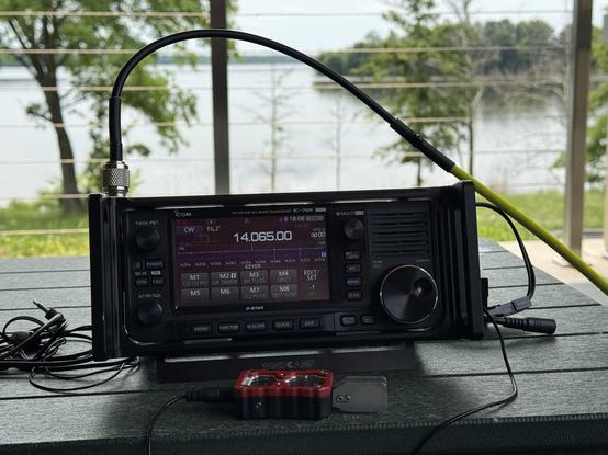 My Icom IC-705 and Modern Morse paddles on a green table. In the background is Crab Orchard Lake.