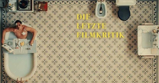 Ein mit symmetrischen Blumenmustern gekacheltes Badezimmer aus der Vogelperspektive und wir sehen Benicio del Toro als Zsa-Zsa Korda in einer vollen Badewanne sitzend zu uns auf blicken. Coverbild des Podcasts "Die Letzte Filmkritik".