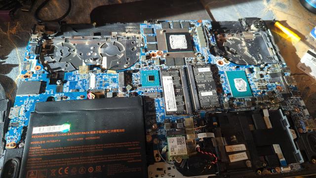 Underside of a System76 Oryx Pro 5 laptop, with the bottom cover, heat sink, and fans removed. There's a bit of dust but it's pretty clean inside.