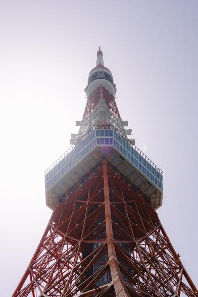 photo of the main floor of the tokyo tower, with the sun shining behind it, with a clear sky in the background