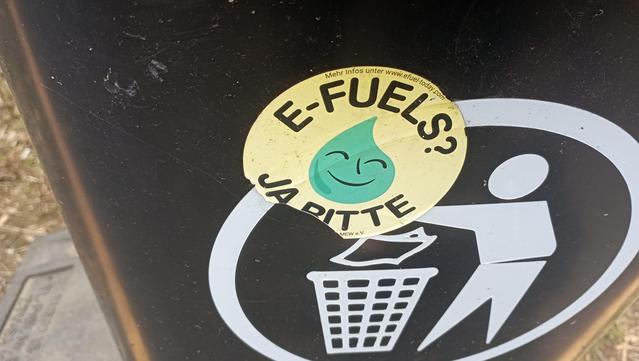 Ein Sticker mit Efuels, ja bitte, auf einem Mülleimer..
