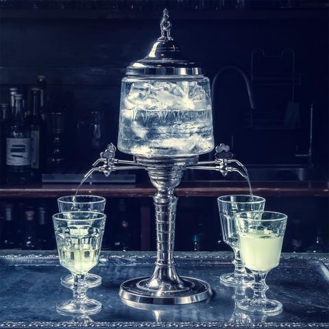 Traditional bar fountain dripping water into absinthe glasses.