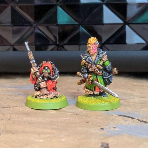 Two brightly painted miniature figures, on short with a long gun in a ted coat and gas mask, the other tall in a green coat with blonde locks and a sword.